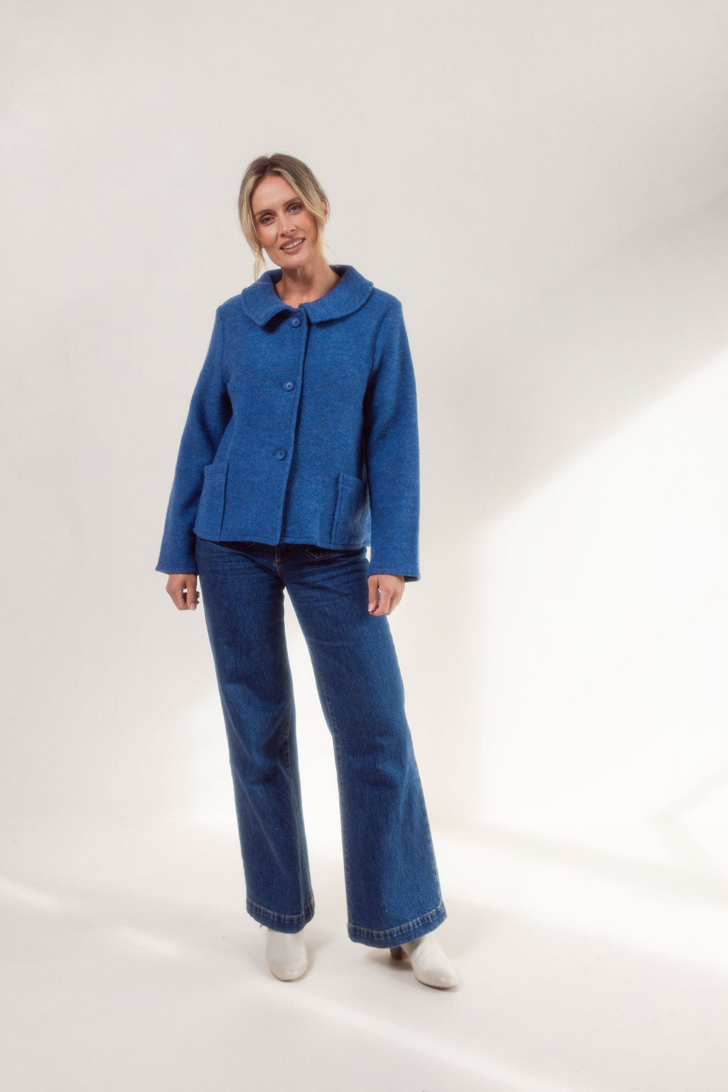 Woman wearing a denim See Saw boiled wool jacket and blue jeans on a white background