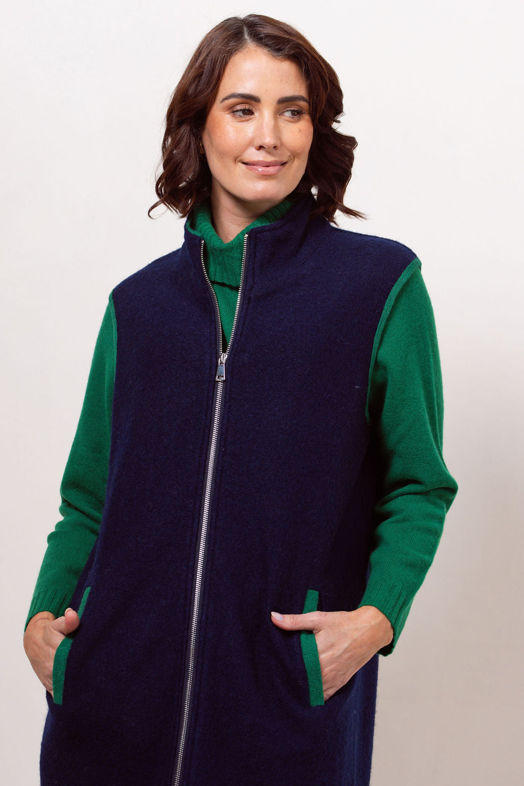 Woman wearing a navy See Saw boiled wool vest over a black long-sleeve shirt against a plain background