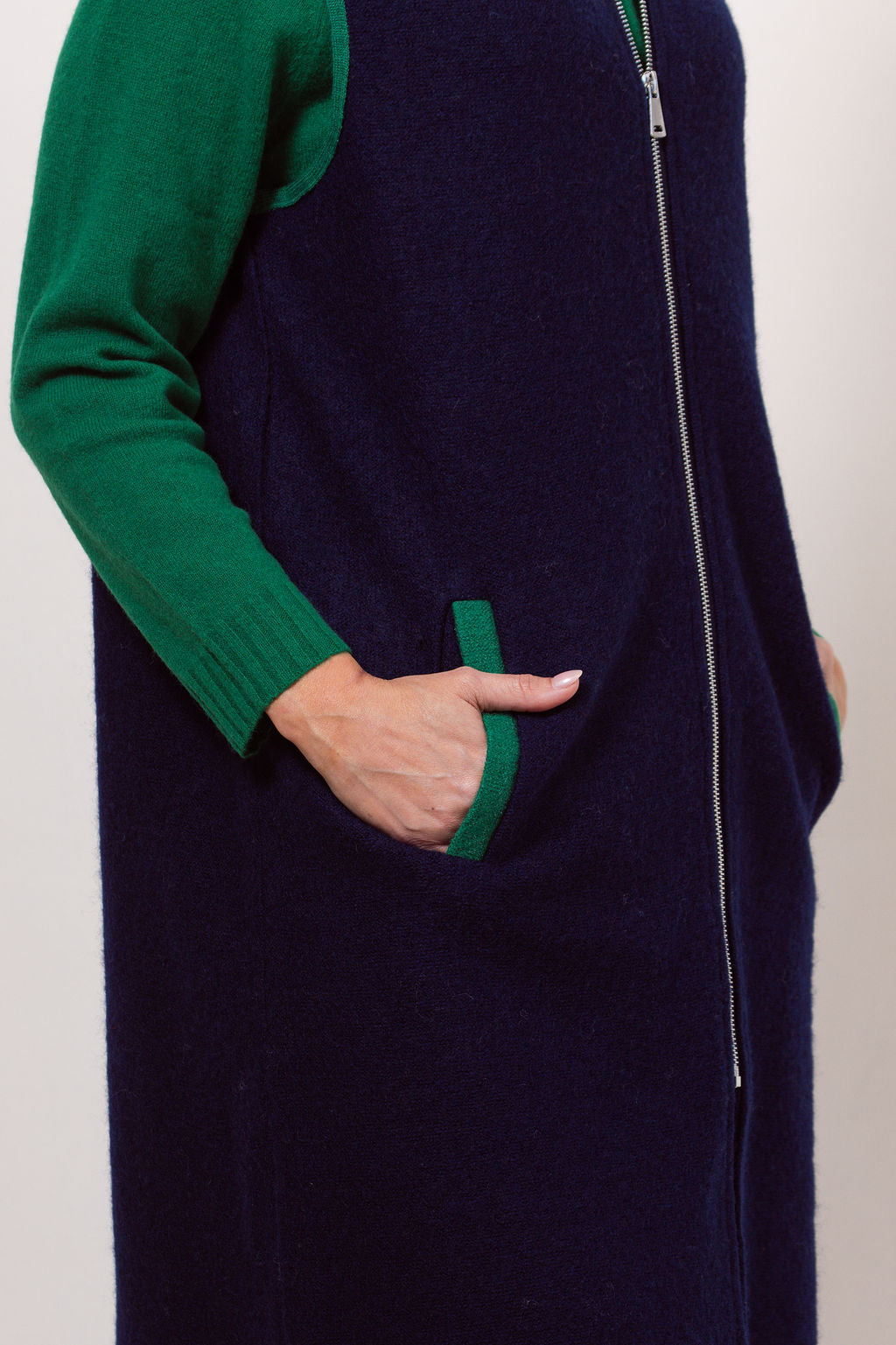 Woman wearing a navy See Saw boiled wool vest over a black long-sleeve shirt against a plain background