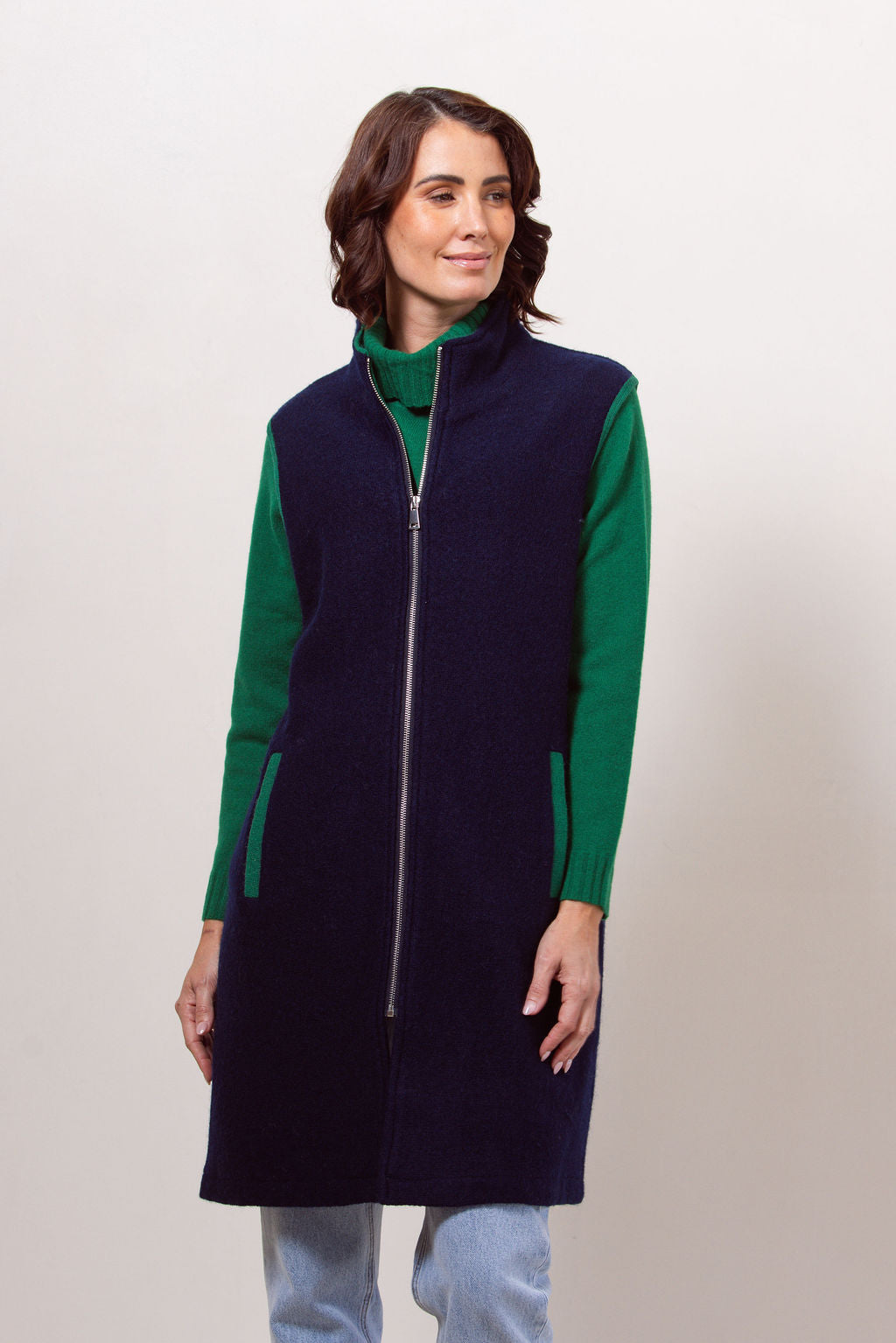 Woman wearing a navy See Saw boiled wool vest over a black long-sleeve shirt against a plain background