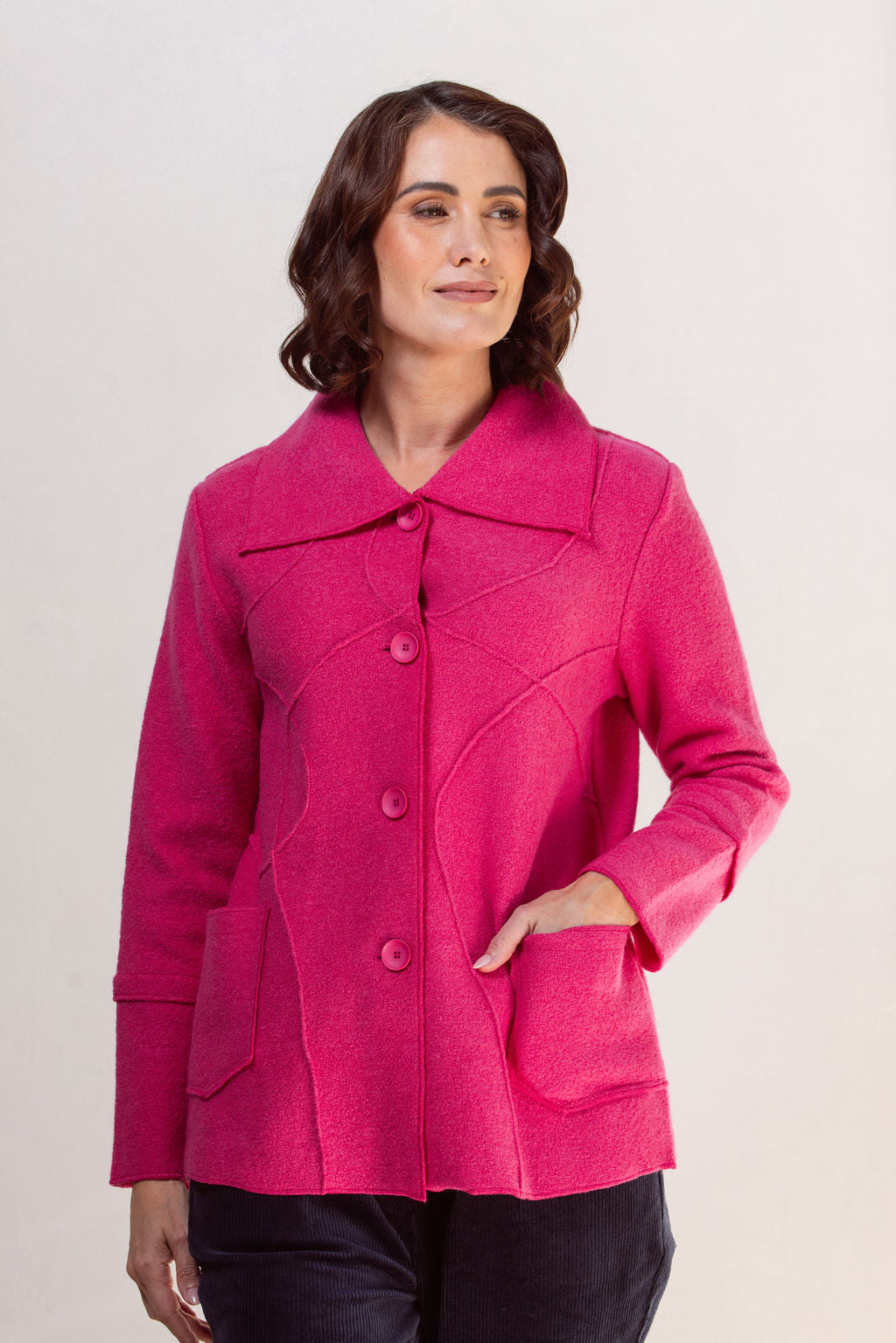 Woman wearing a bright pink See Saw Boiled wool coat against a plain background