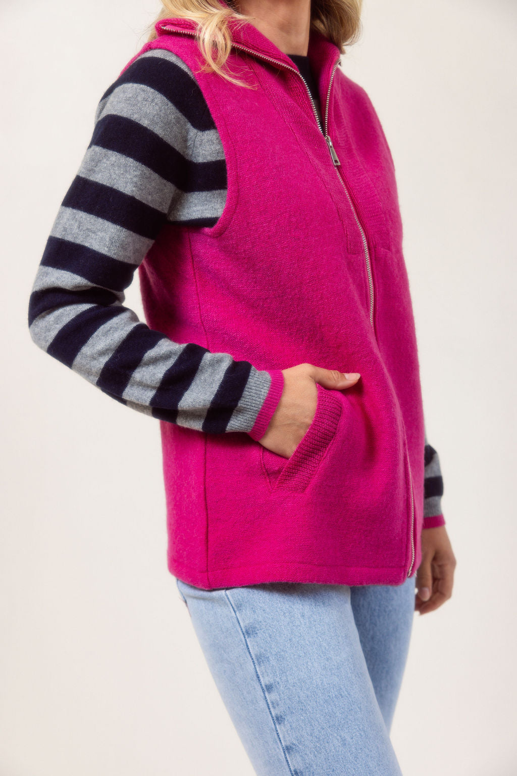 Woman wearing a See Saw pink zip-up vest over a white shirt with a plain background.