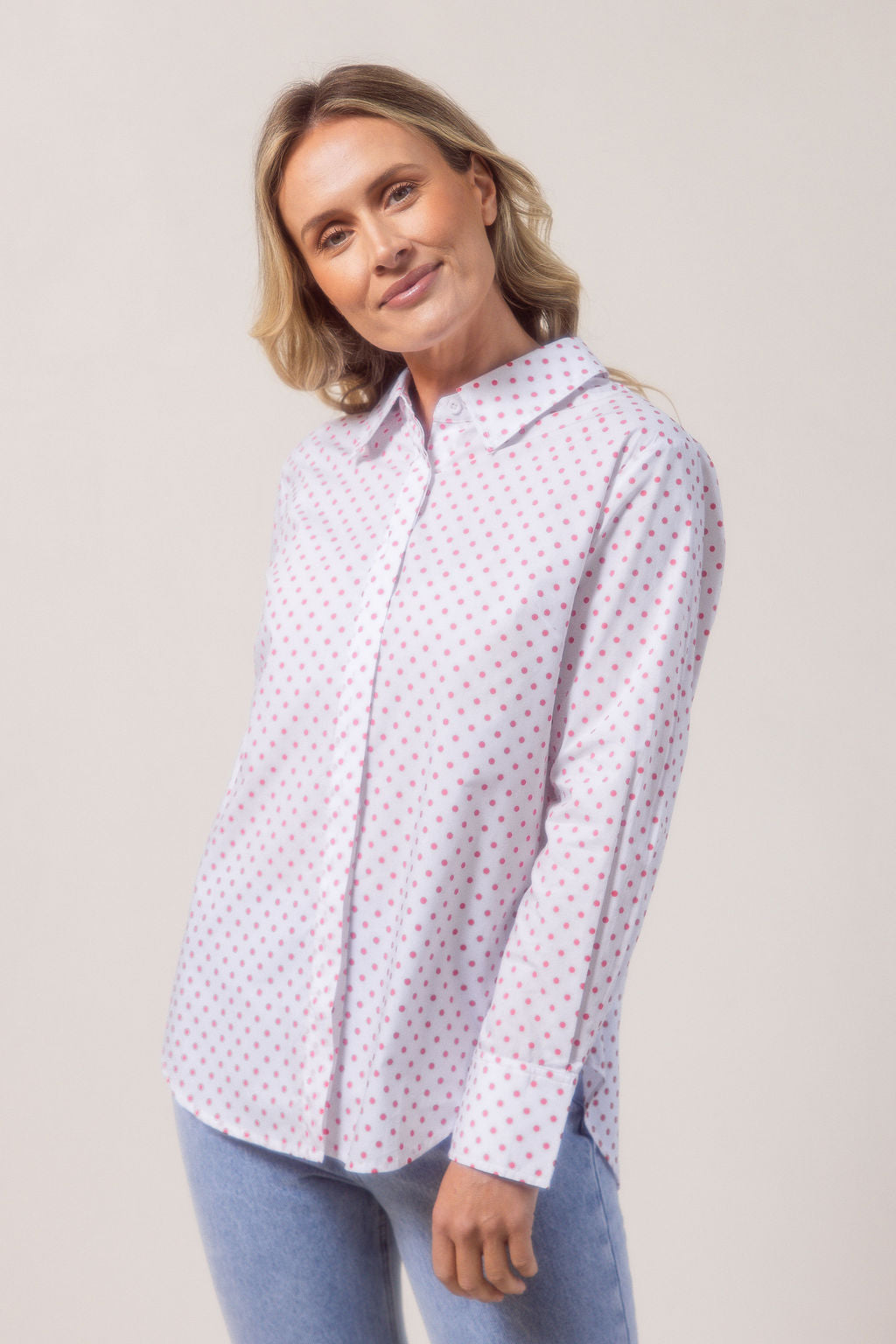Woman wearing a classic white See Saw shirt with spot detail in a bright room with a vase and plant in the background
