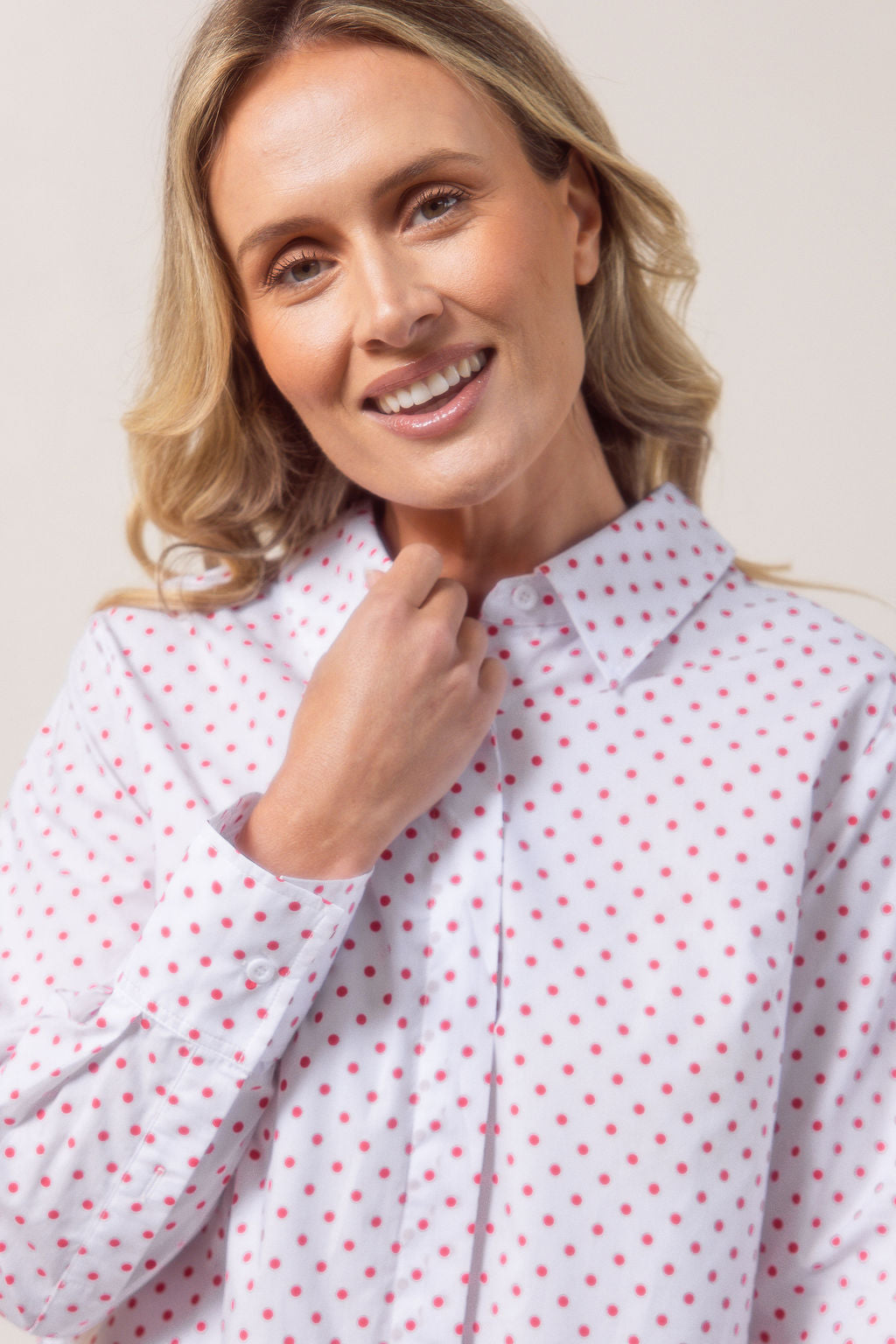 Woman wearing a classic white See Saw shirt with spot detail in a bright room with a vase and plant in the background