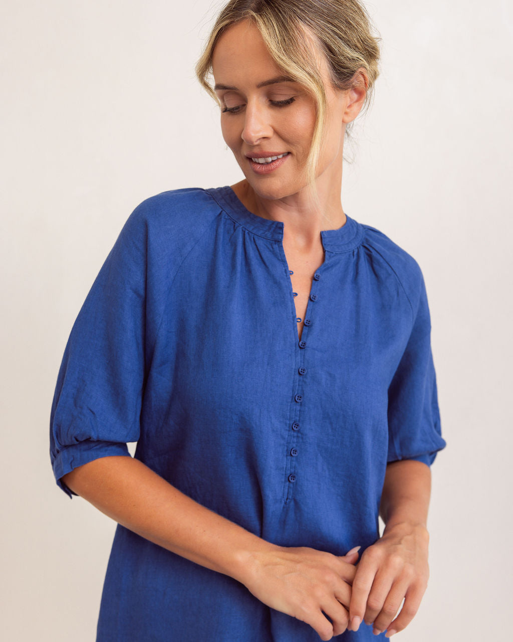 Woman wearing a see saw linen dress with button detail in denim colour against a plain background See Saw Linen Cuff Sleeve Dress