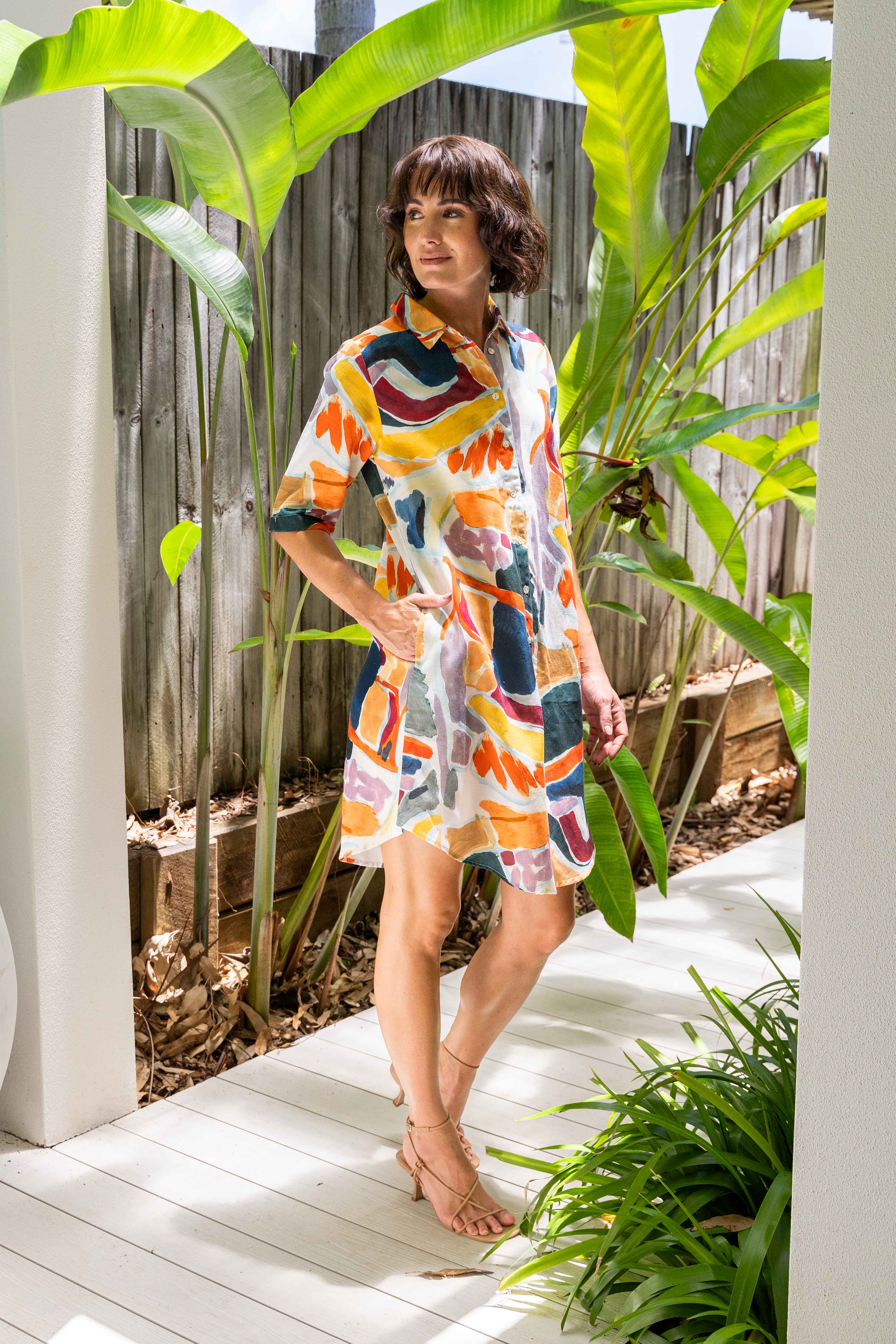 Woman in a colorful dress standing outdoors with plants around. See Saw Linen Shirtmaker Dress