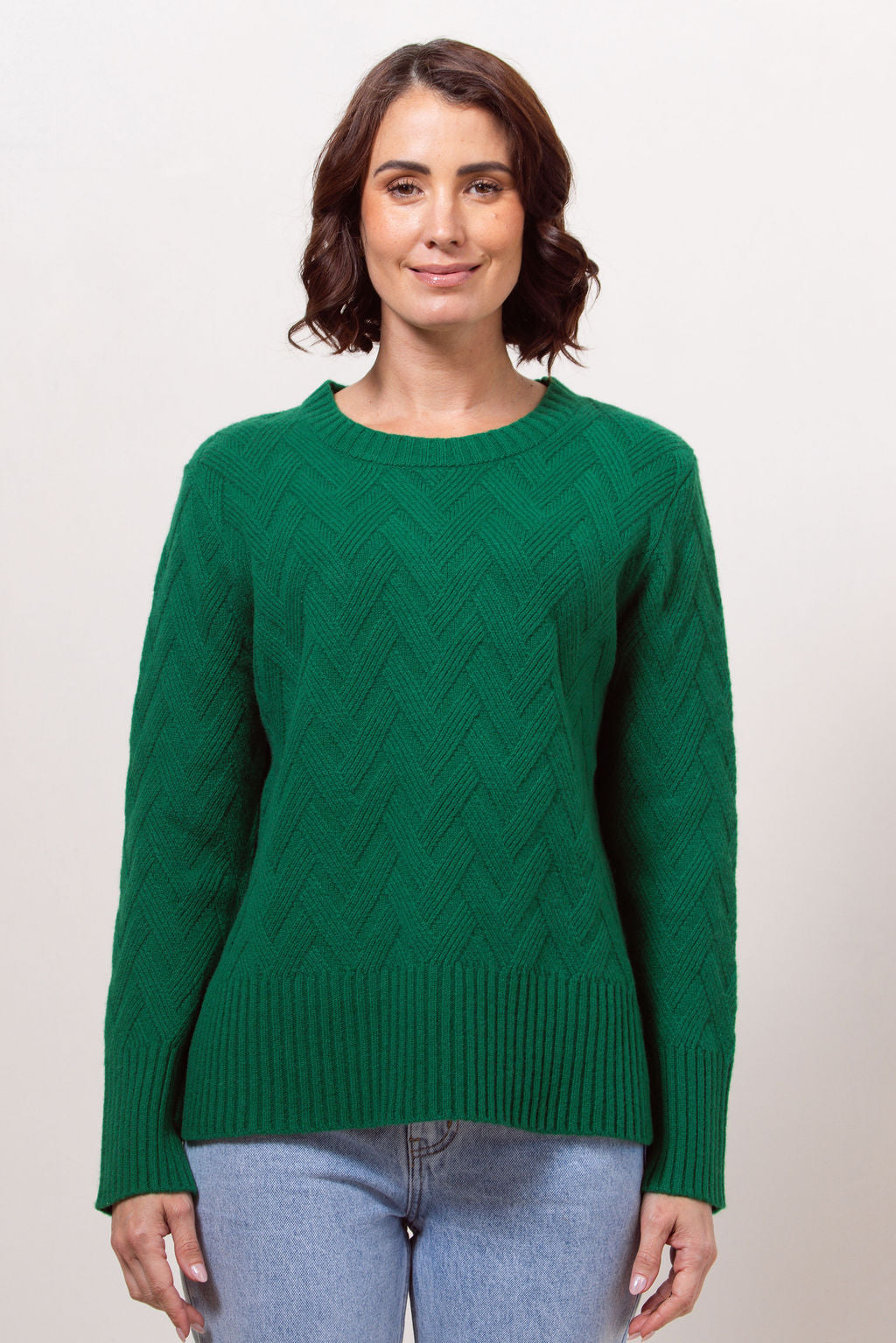 Woman wearing a green See Saw sweater against a plain background
