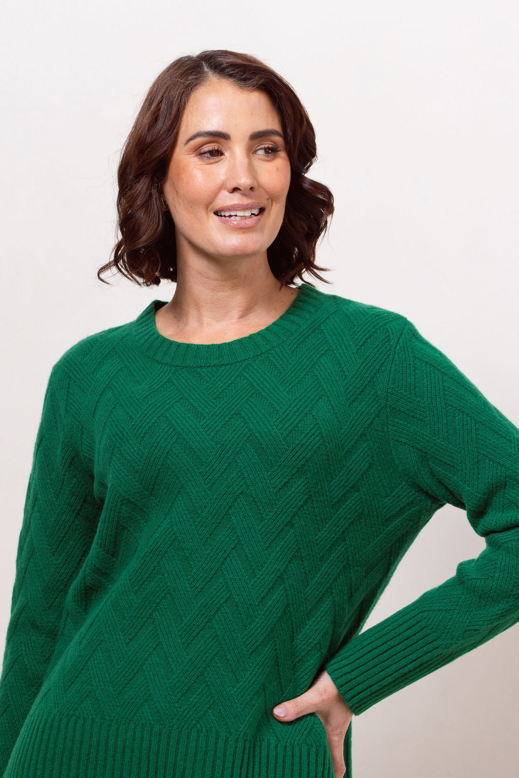 Woman wearing a green See Saw sweater against a plain background