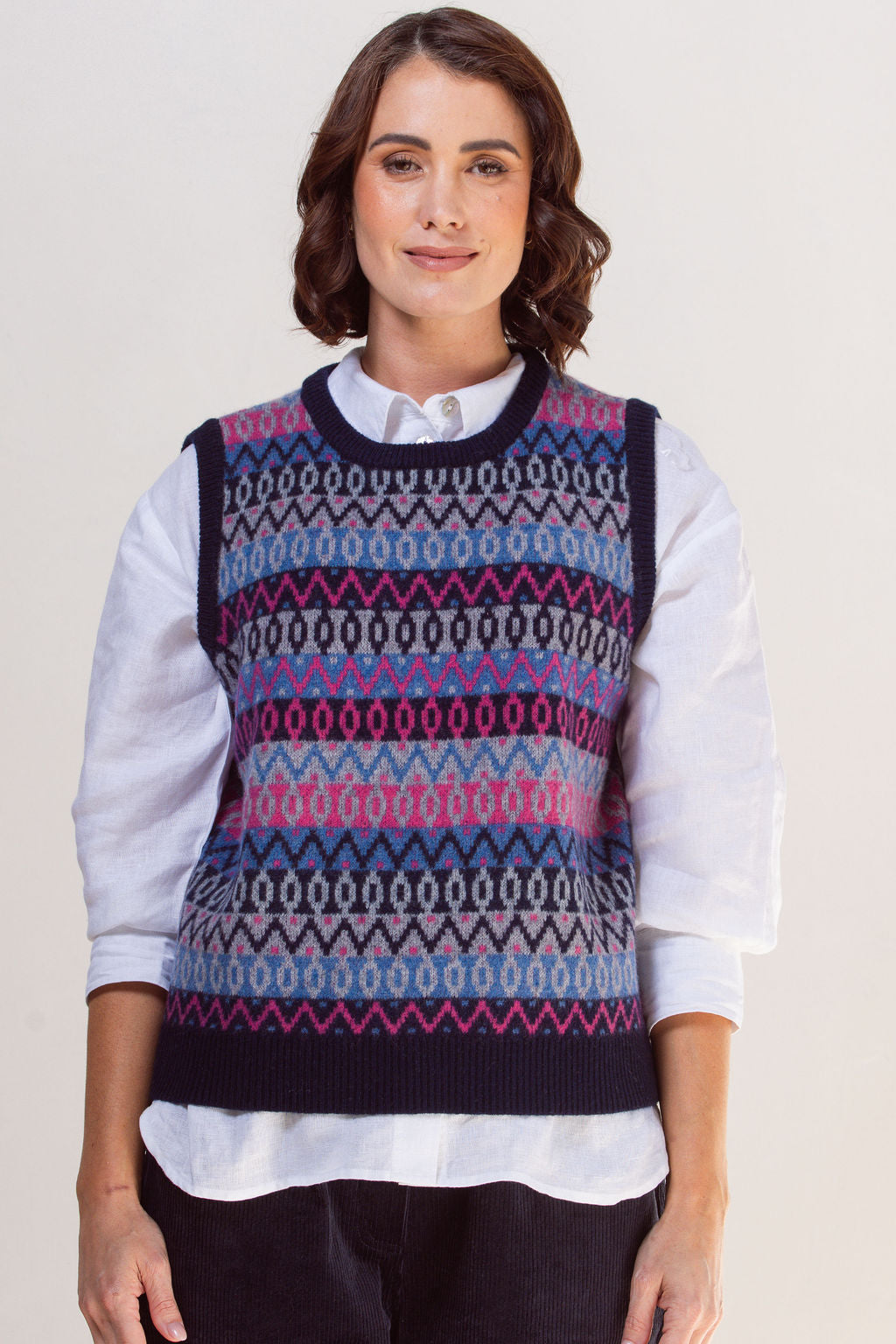 Woman wearing a See Saw jacquard patterned sweater vest over a white shirt on a plain background