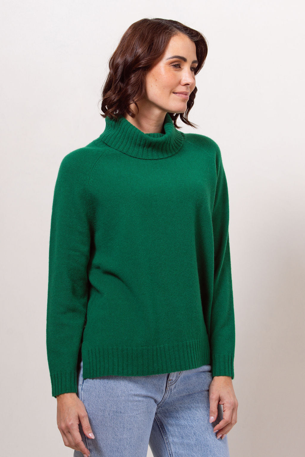 Woman wearing a green See Saw roll neck sweater against a white background