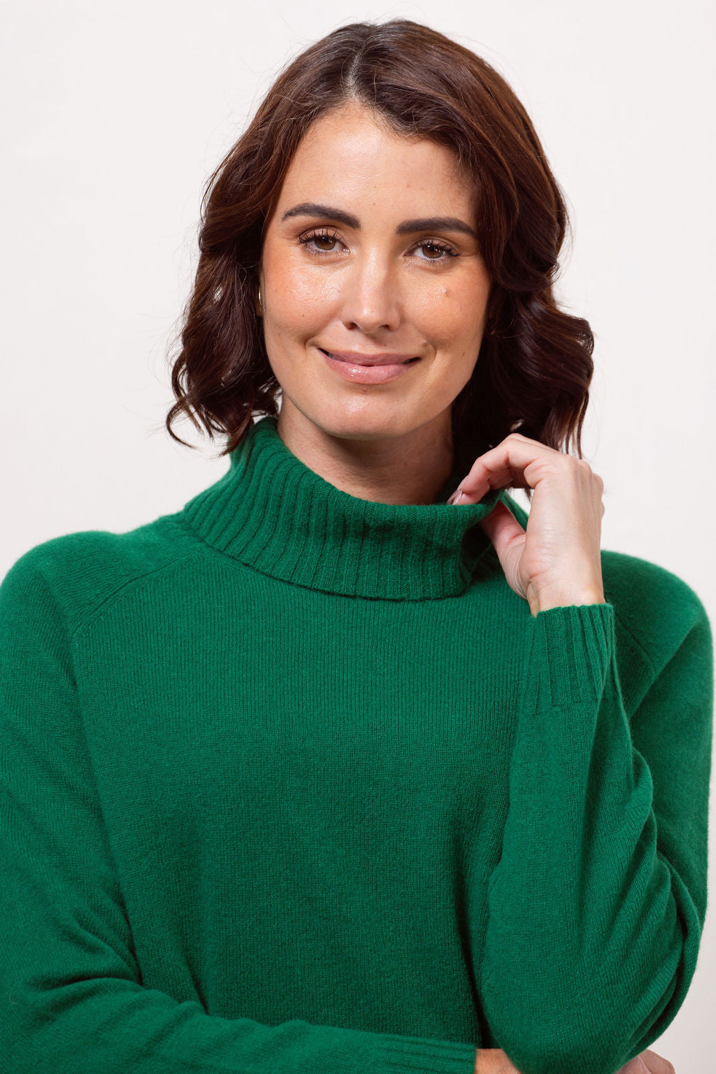 Woman wearing a green See Saw roll neck sweater against a white background