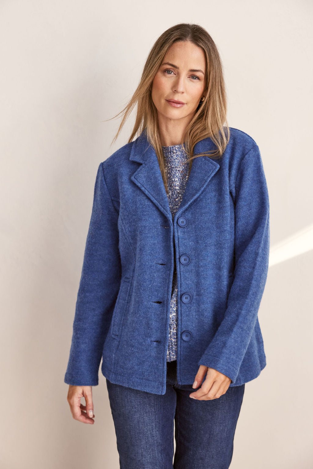 Woman wearing green boiled wool See Saw blazer in denim with a white background