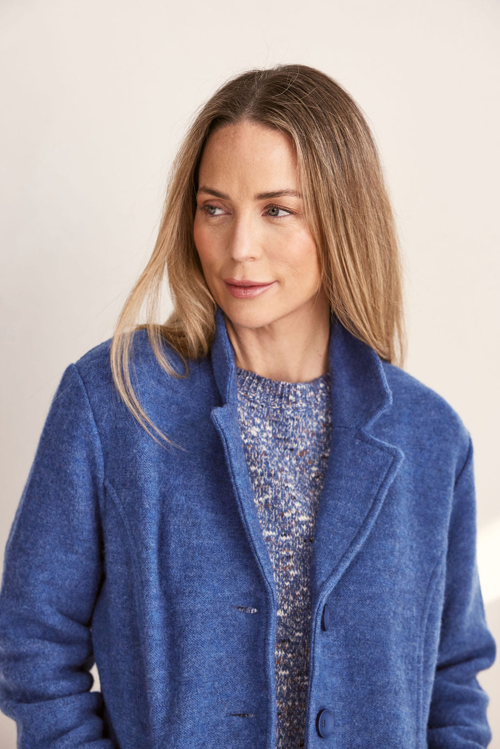 Woman wearing green boiled wool See Saw blazer in denim with a white background