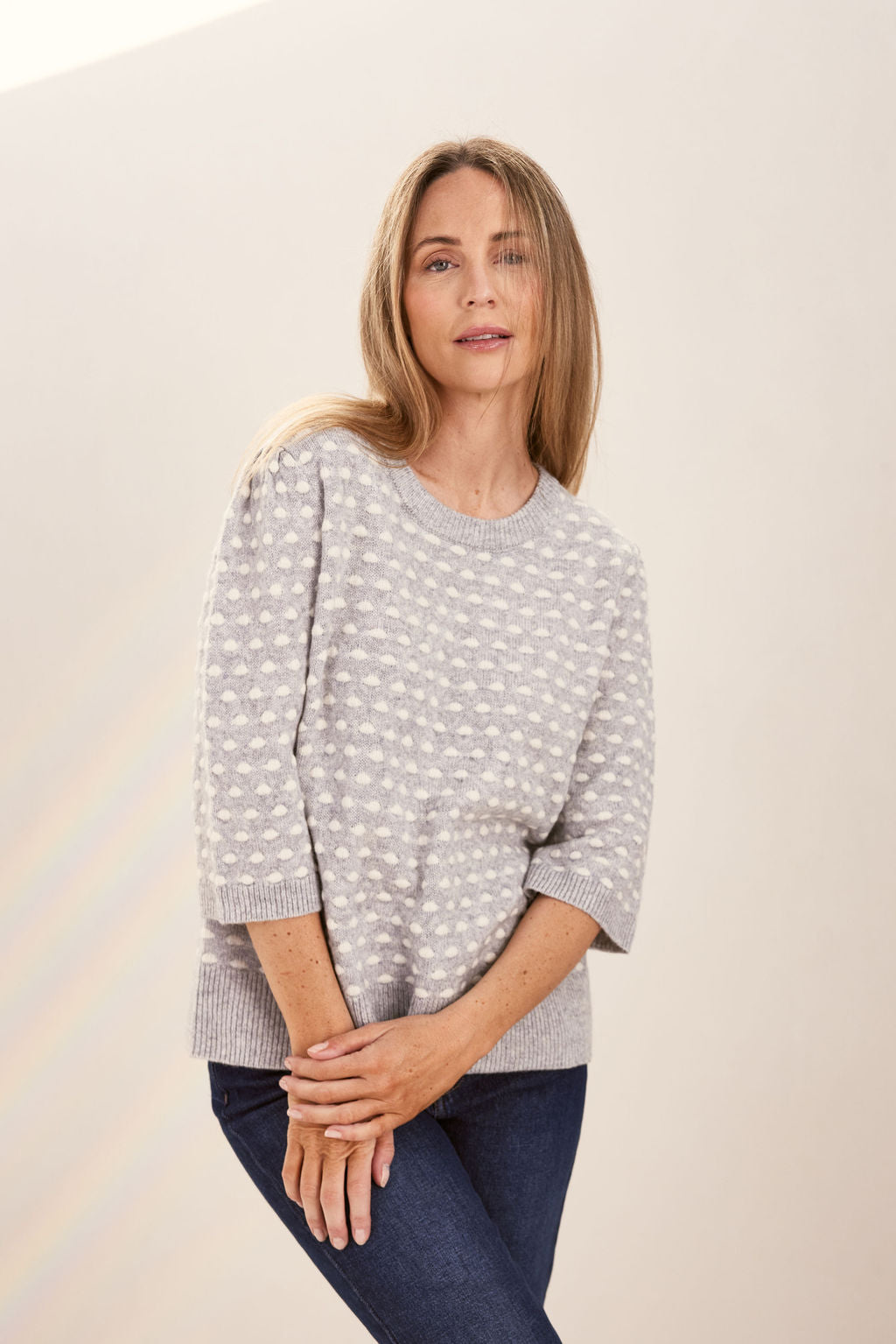 Woman wearing a patterned silver and white See Saw sweater against a plain background