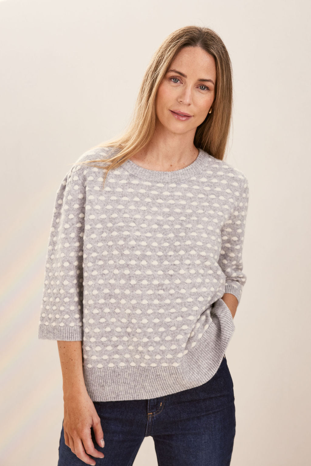 Woman wearing a patterned silver and white See Saw sweater against a plain background
