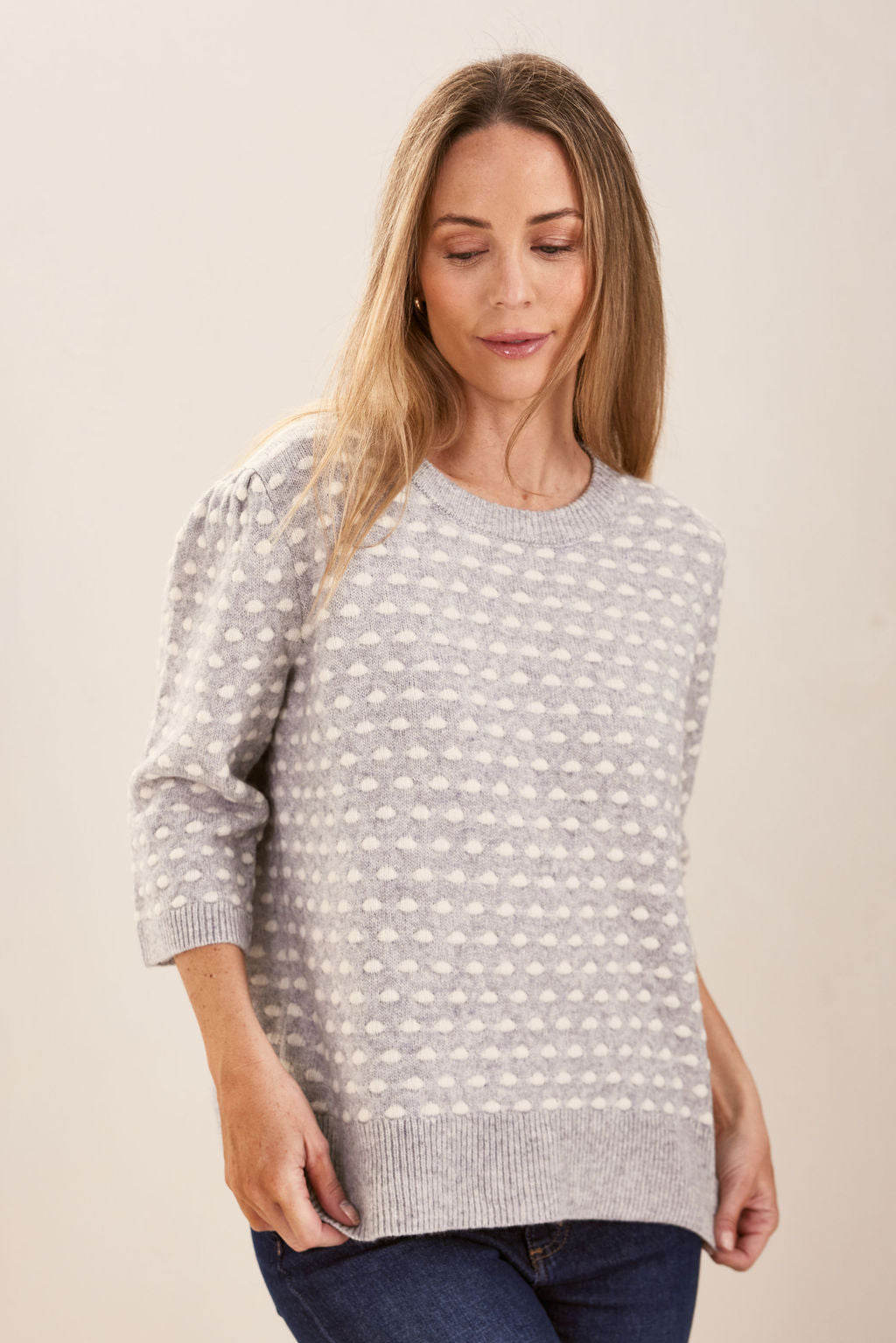 Woman wearing a patterned silver and white See Saw sweater against a plain background