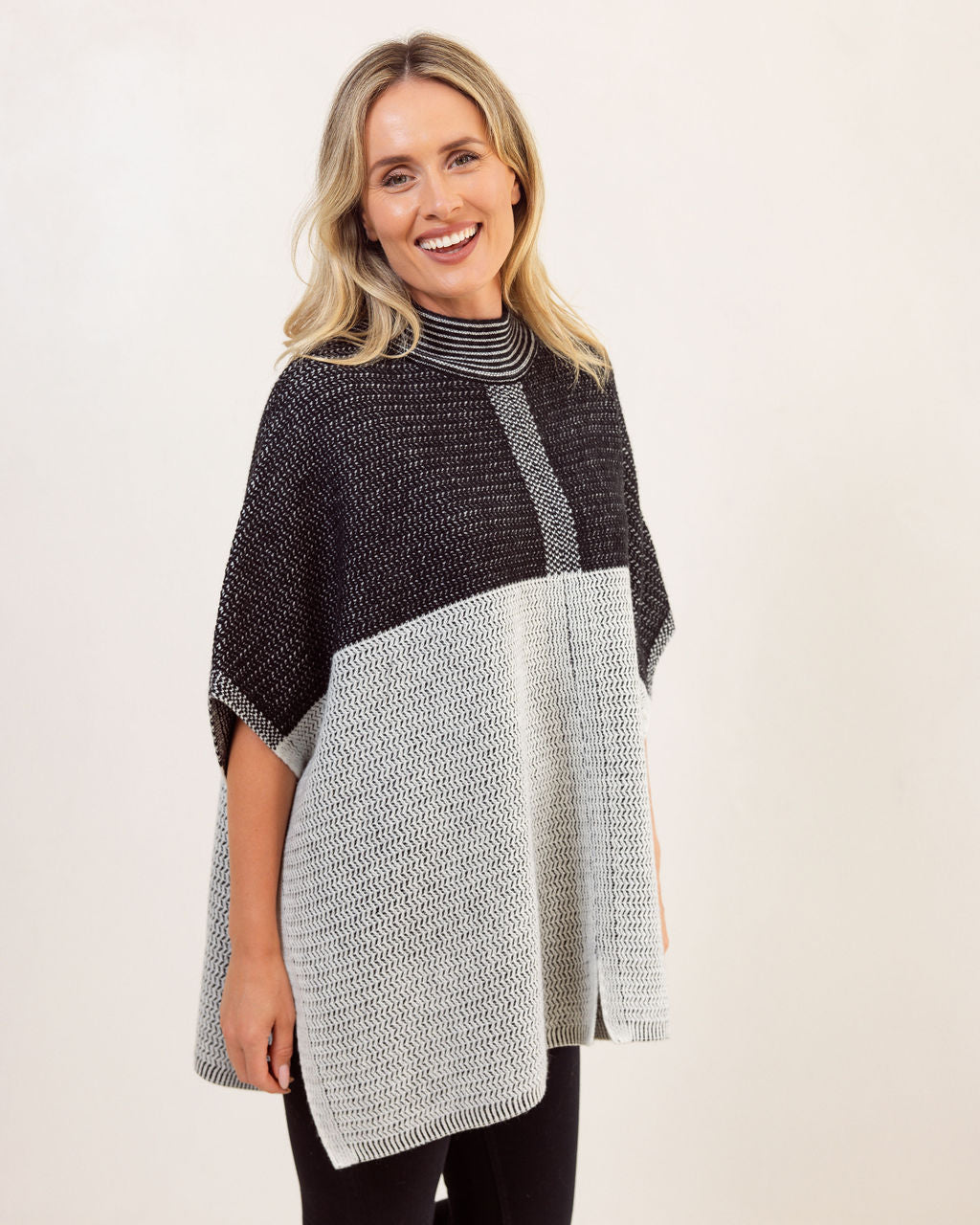 Woman wearing a black and gray See Saw Wool patterned poncho against a white background