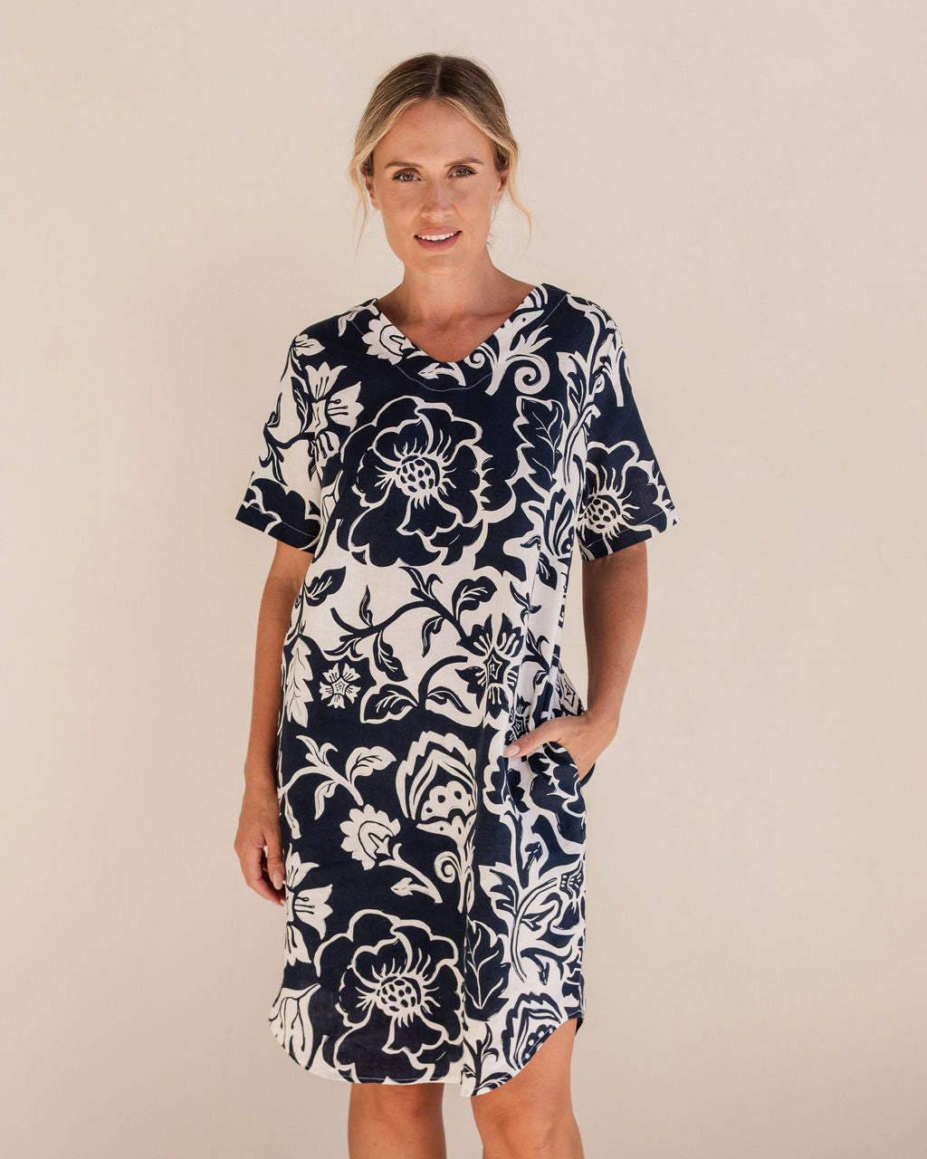 Woman wearing a navy floral dress on a beige background. See Saw Linen Soft V Neck Print Dress