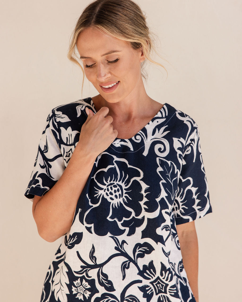 Woman wearing a navy floral dress on a beige background. See Saw Linen Soft V Neck Print Dress