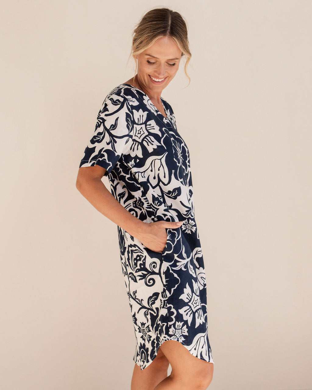 Woman wearing a navy floral dress on a beige background. See Saw Linen Soft V Neck Print Dress