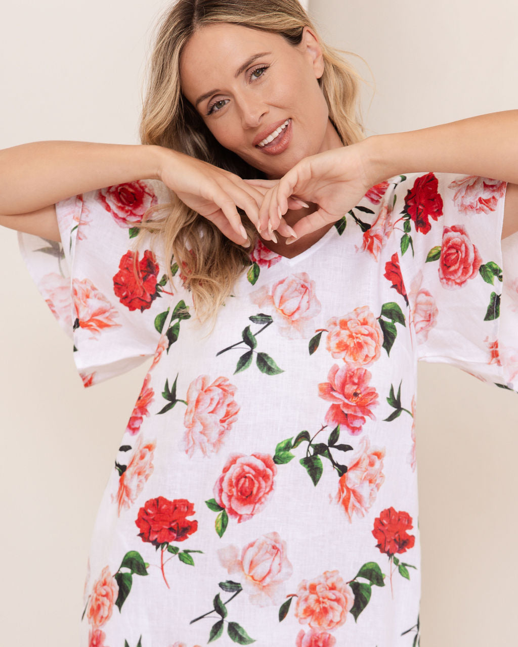 Woman wearing a See Saw linen flutter sleeve rose dress with a plain background