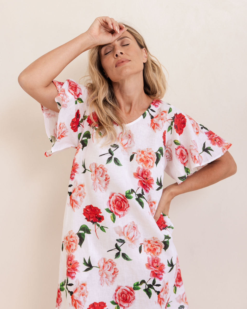 Woman wearing a See Saw linen flutter sleeve rose dress with a plain background