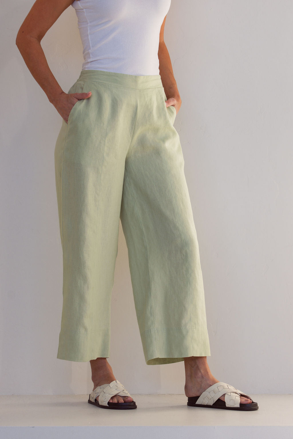 Person wearing light green See Saw Linen pants and white top on a plain background