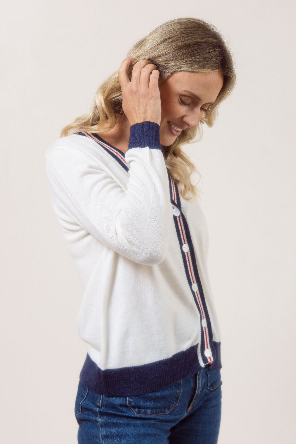 Woman wearing a white See Saw Merino Wool cardigan with blue and red accents on a plain background