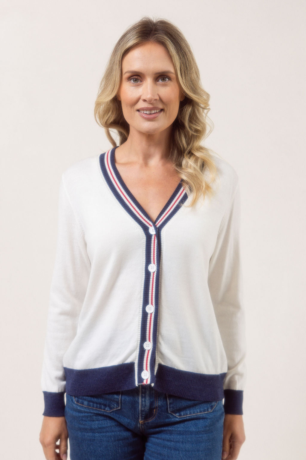 Woman wearing a white See Saw Merino Wool cardigan with blue and red accents on a plain background