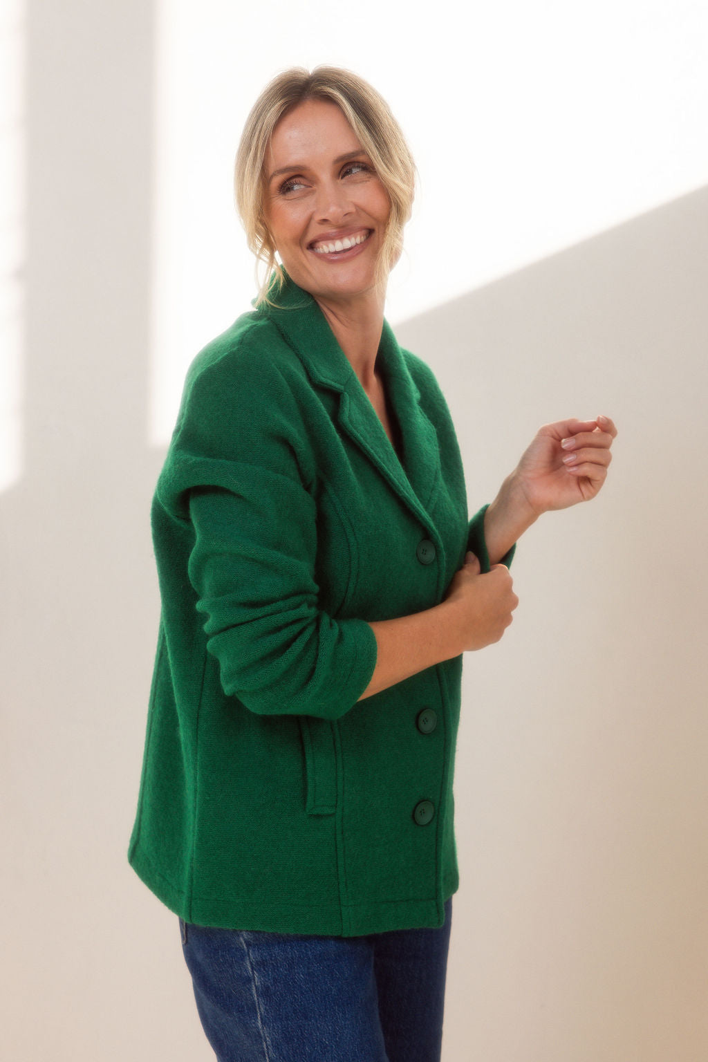 Woman wearing green boiled wool See Saw blazer in green with a white background