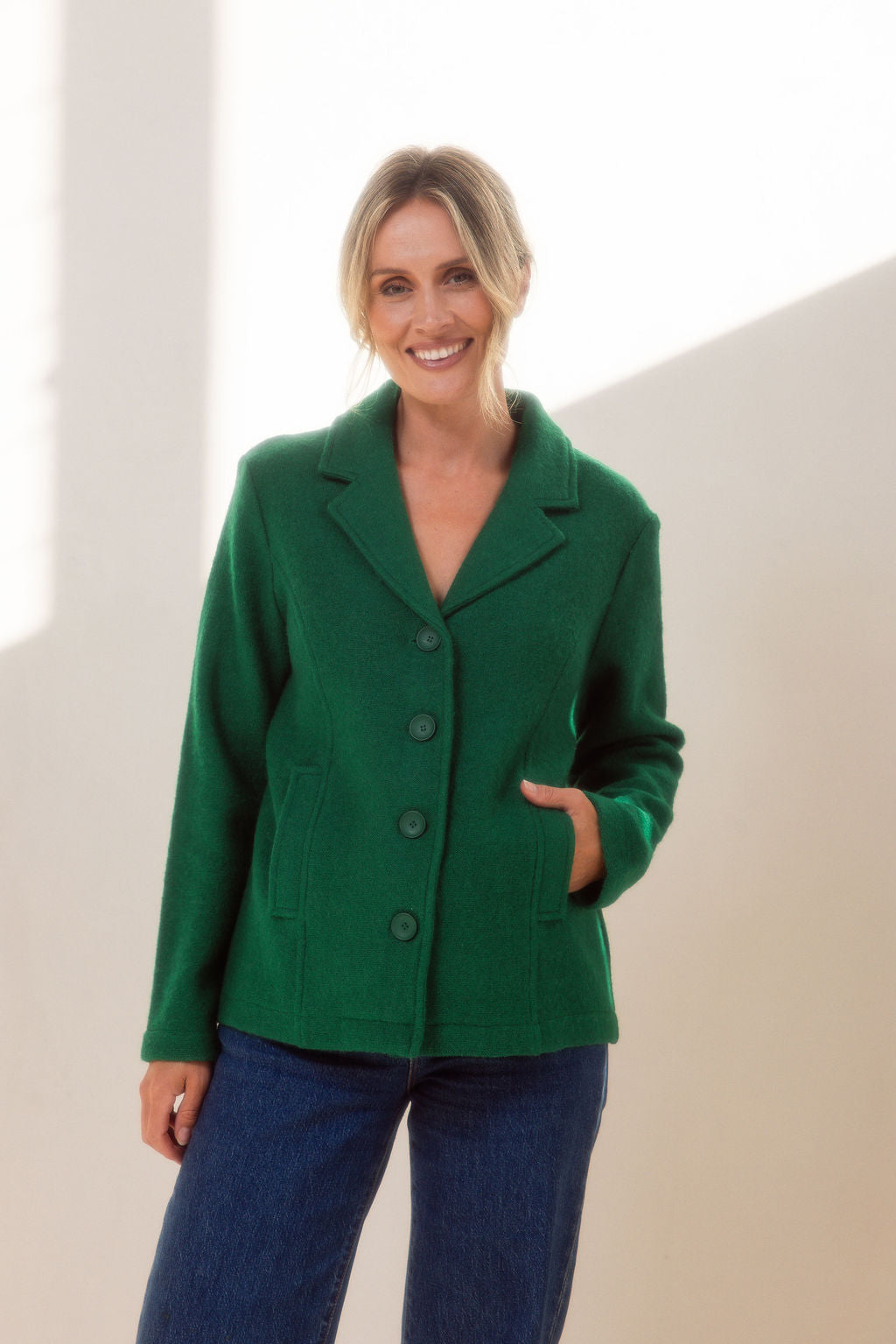 Woman wearing green boiled wool See Saw blazer in green with a white background