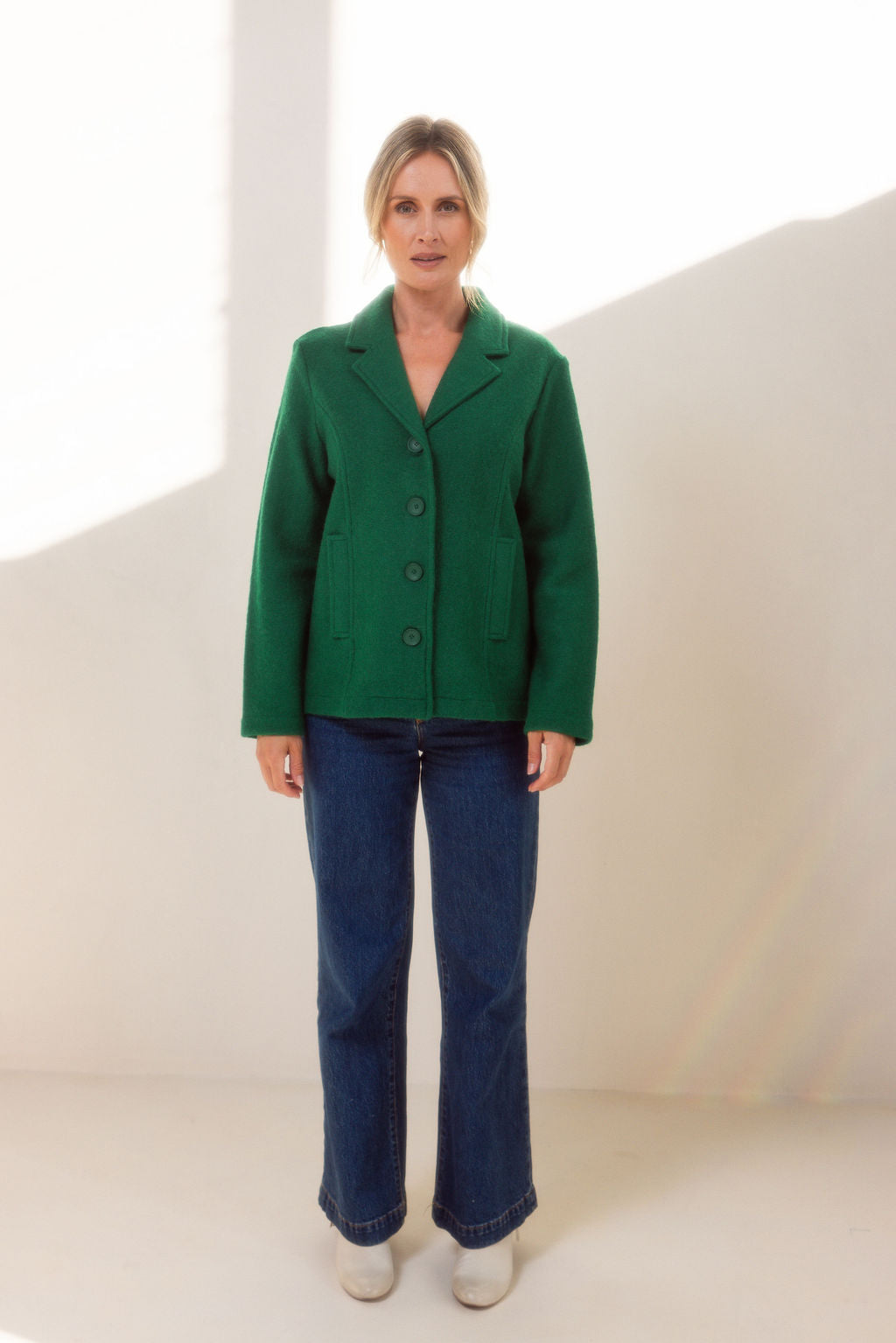 Woman wearing green boiled wool See Saw blazer in green with a white background