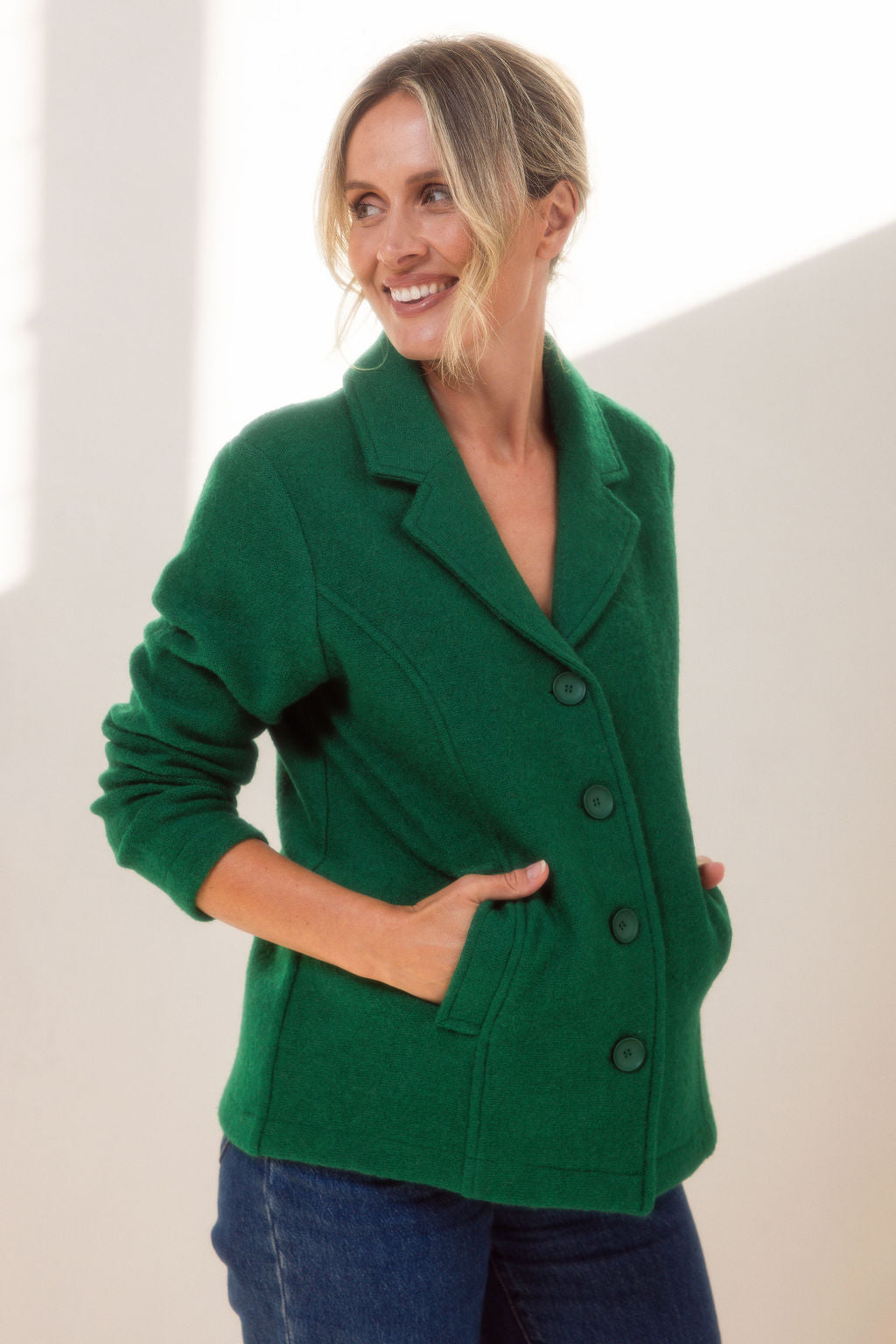 Woman wearing green boiled wool See Saw blazer in green with a white background