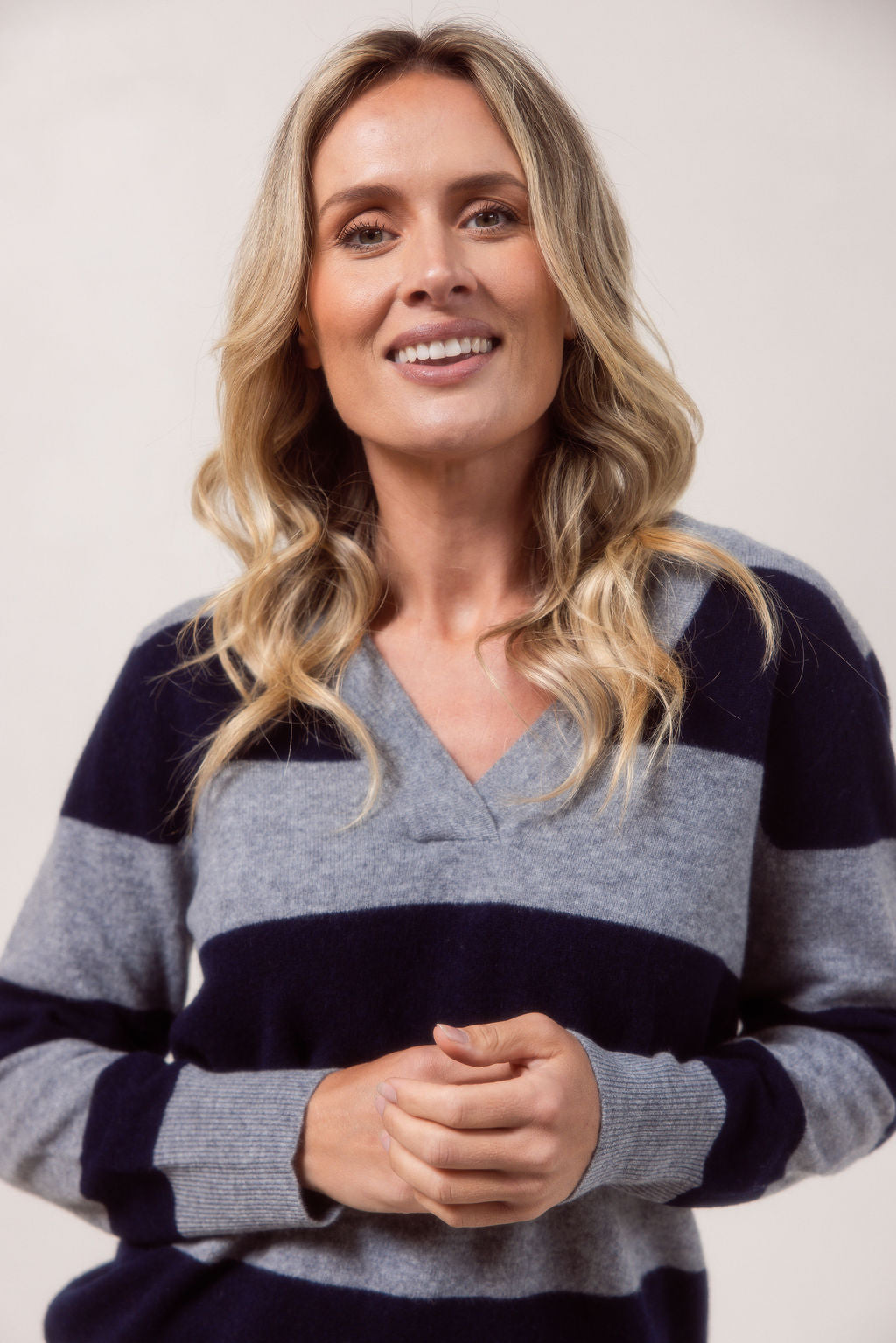 Woman wearing a striped Merino Wool See Saw sweater and jeans against a plain background