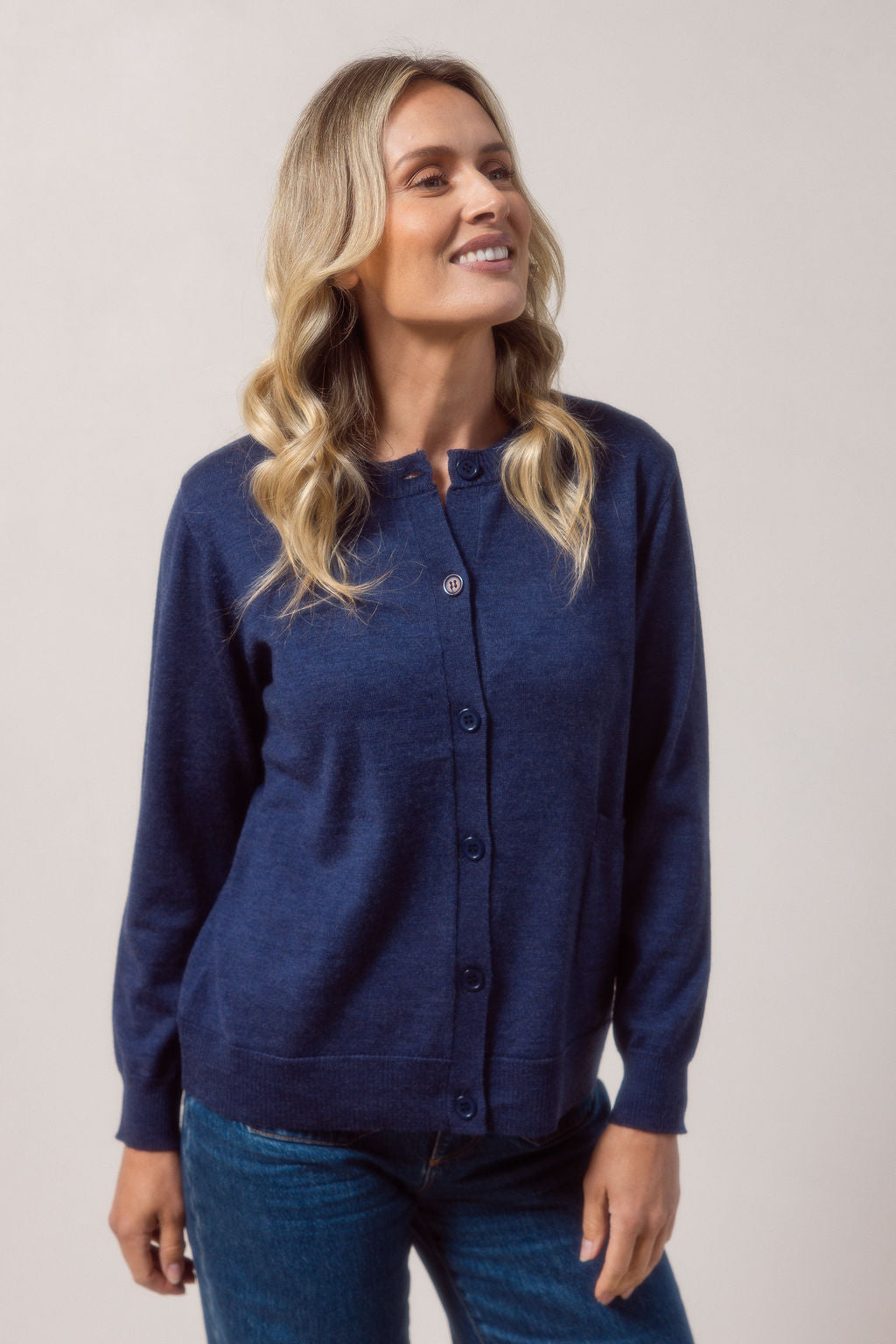 Woman wearing a merino wool See Saw indigo cardigan and blue jeans against a plain background