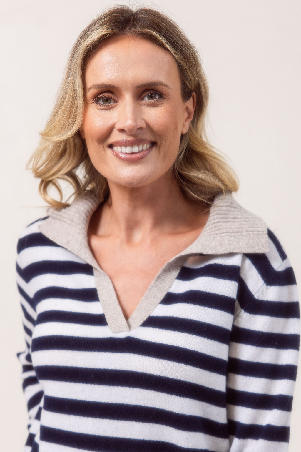 Woman wearing a see Saw Merino Wool navy and white striped sweater with a light gray collar against a plain background