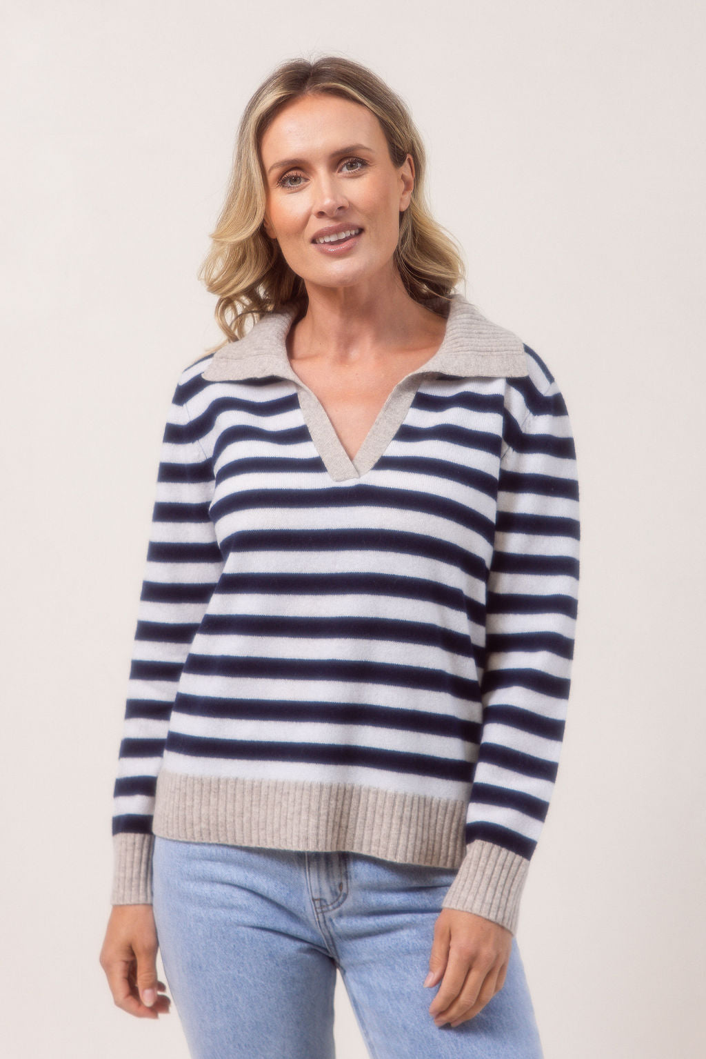 Woman wearing a see Saw Merino Wool navy and white striped sweater with a light gray collar against a plain background