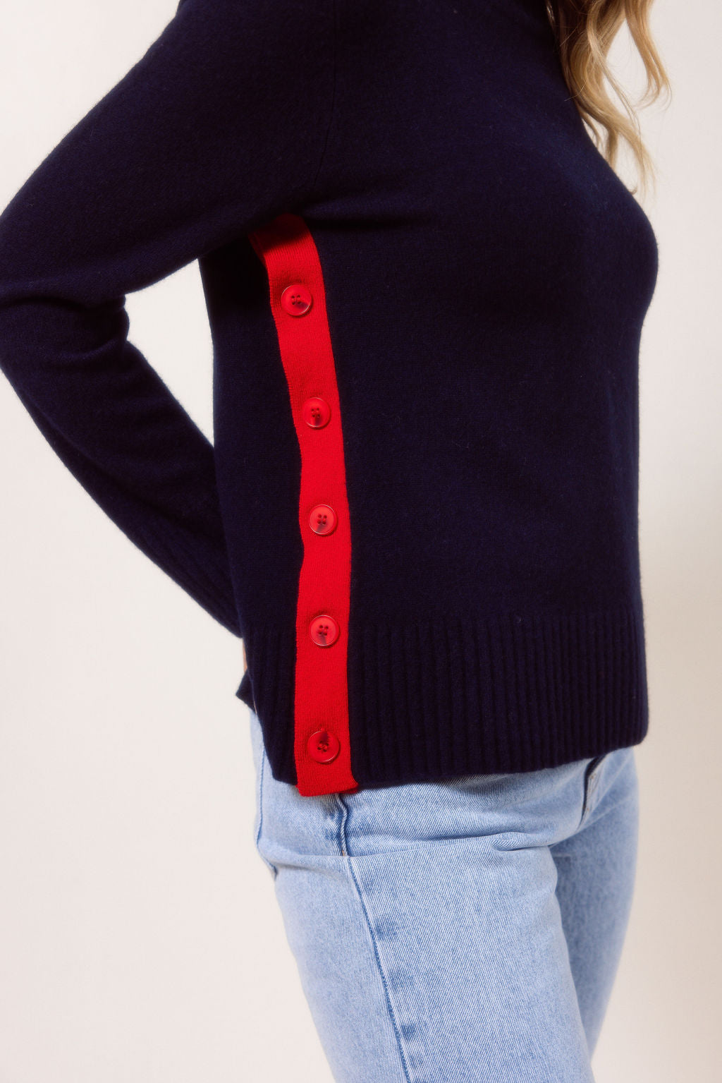 Woman wearing a Merino Wool See Saw sweater in navy sweater with red accents on a plain background
