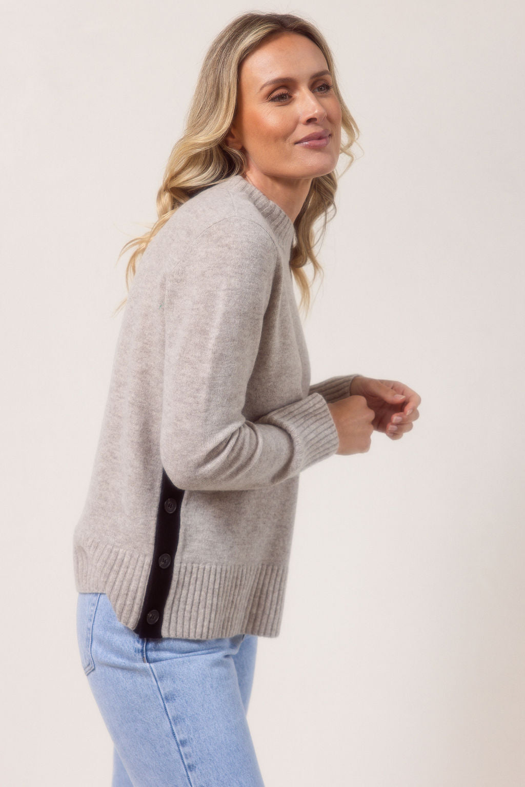 Woman wearing a Merino Wool See Saw sweater in wheat with Black accents on a plain background