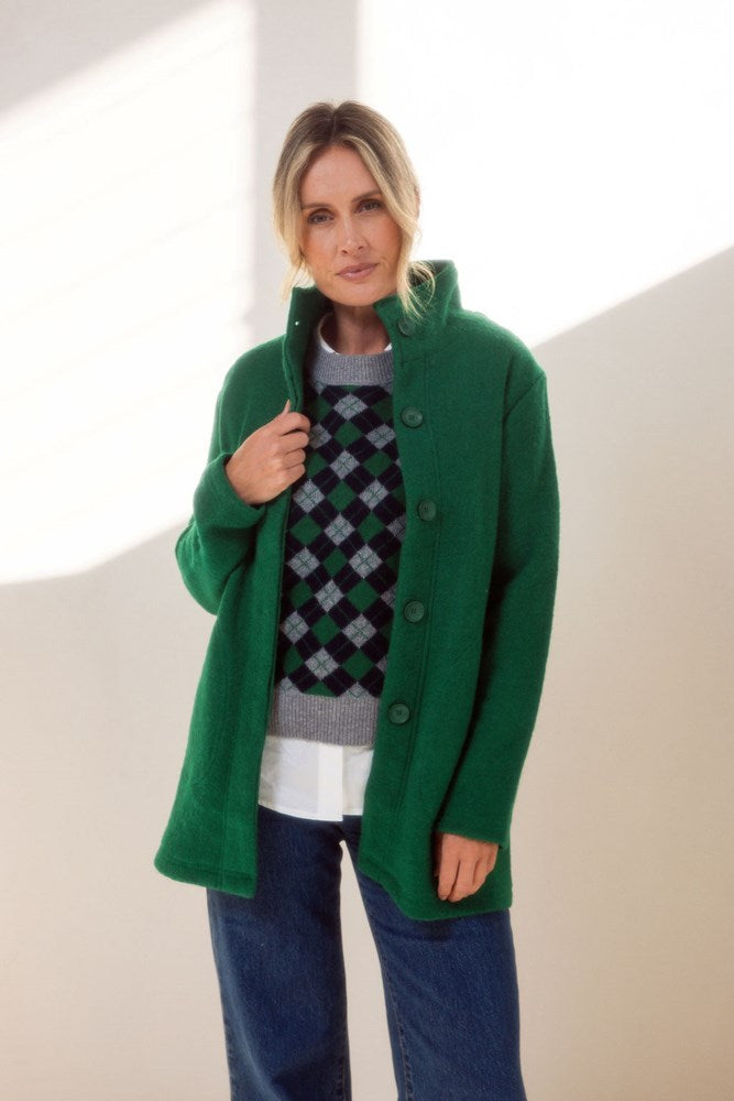 Woman wearing a green See Saw boiled wool jacket with funnel neck standing in front of a plain background
