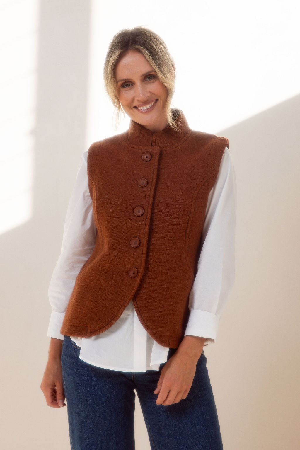 Woman wearing a copper See Saw vest over a plaid shirt with a plain background