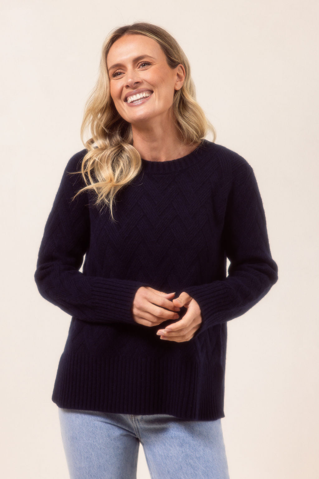 Woman wearing a navy See Saw sweater against a beige background