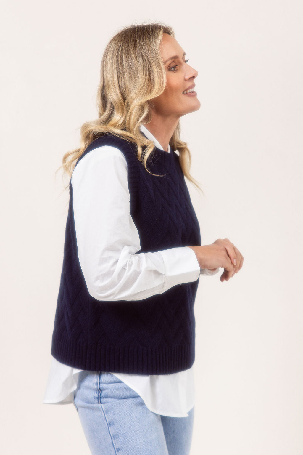 Woman wearing a See Saw Navy Merino Wool knitted vest over a white shirt on a plain background