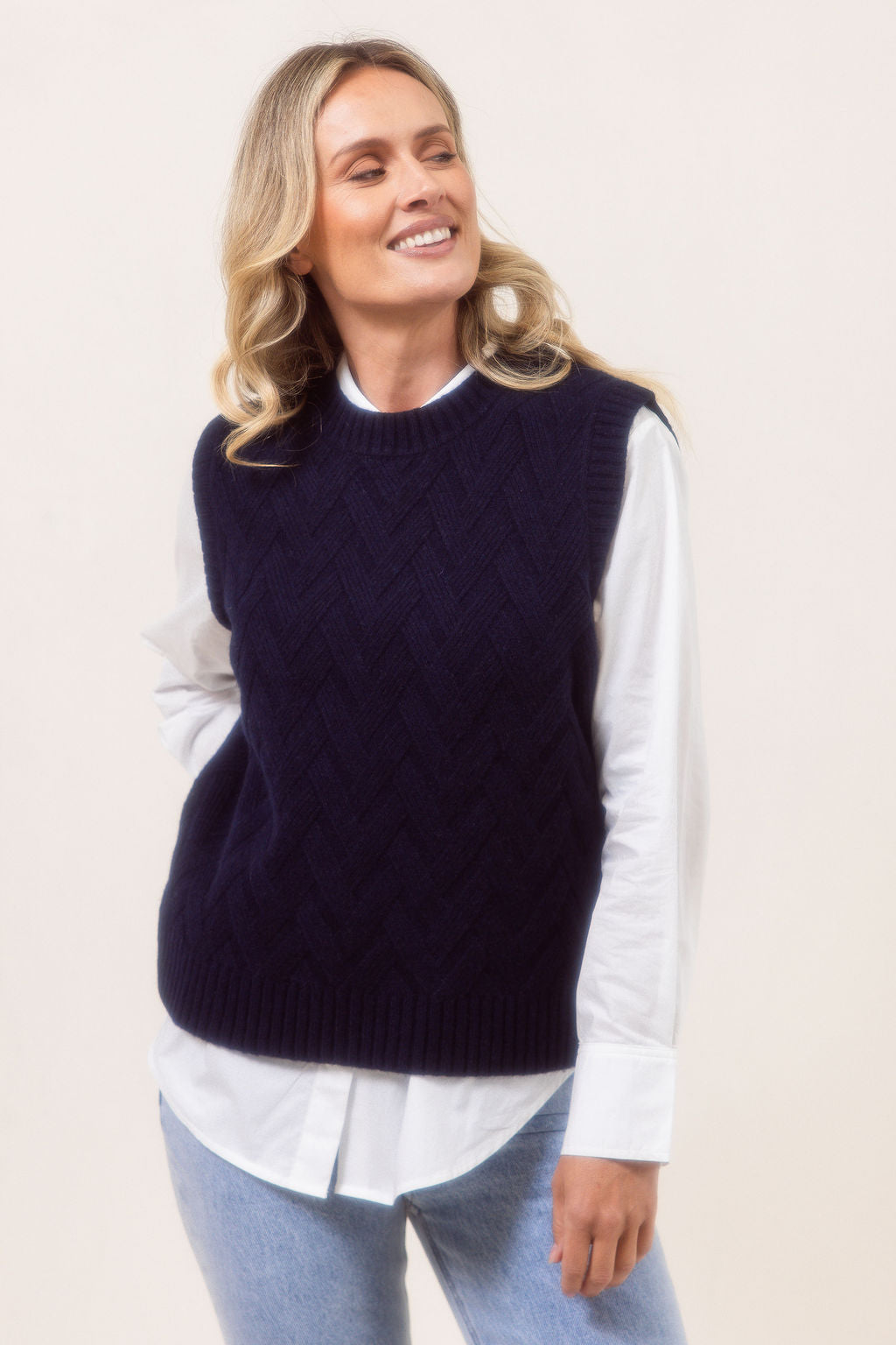 Woman wearing a See Saw Navy Merino Wool knitted vest over a white shirt on a plain background