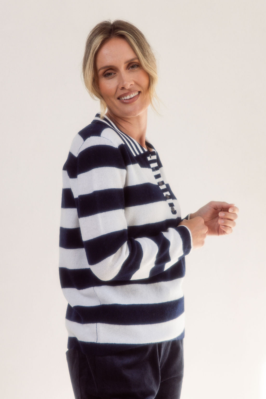 Woman wearing a merino wool See Saw black and white striped sweater on a plain background