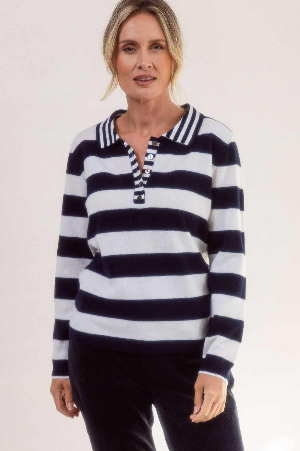 Woman wearing a merino wool See Saw black and white striped sweater on a plain background
