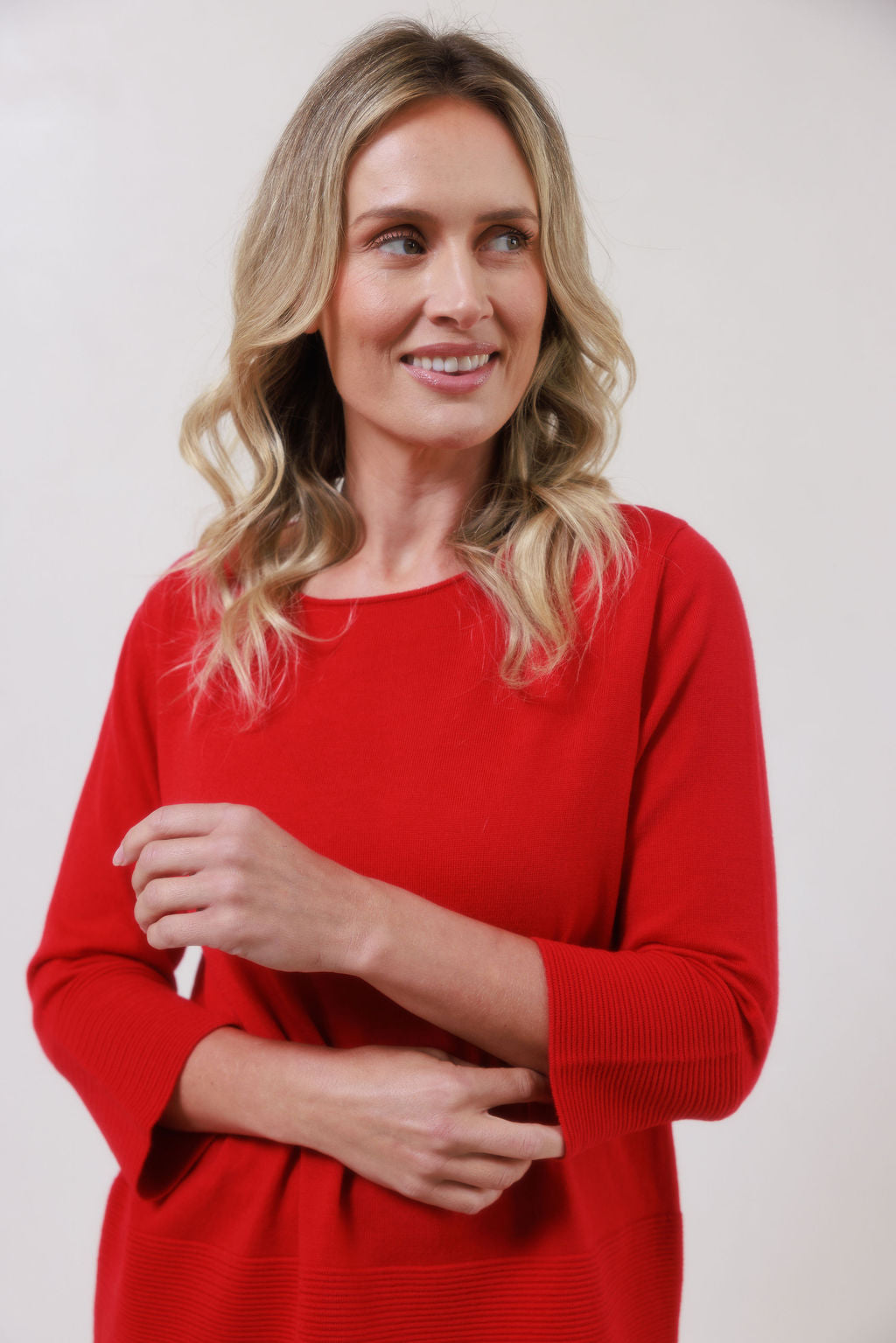 Woman wearing a red See Saw Merino Wool sweater and patterned scarf against a white background