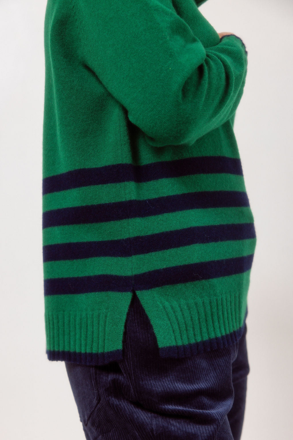 Woman wearing a Green See Saw Merino Wool sweater with a striped design on a white background