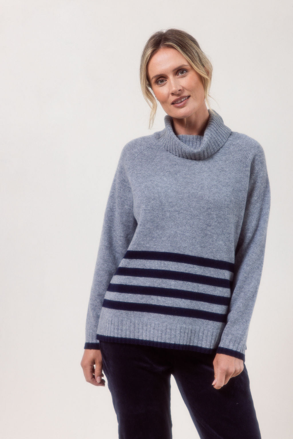 Woman wearing a silver See Saw Merino Wool sweater with a striped design on a white background