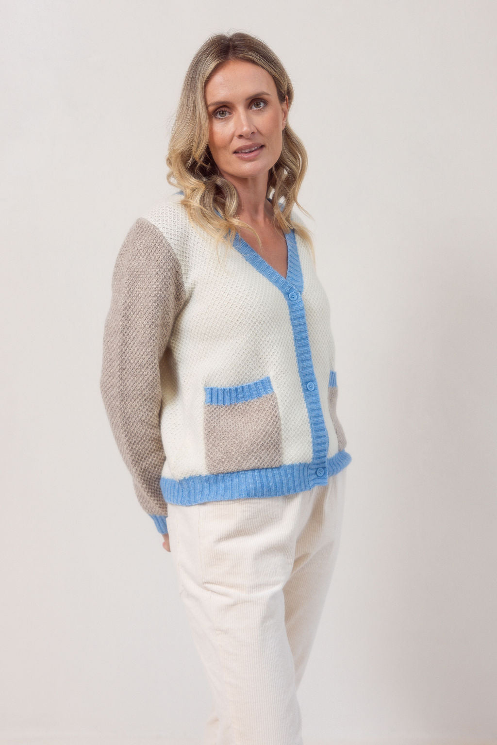 Woman wearing a Moss Stitch See Saw powder blue and beige cardigan with brown accents on a white background